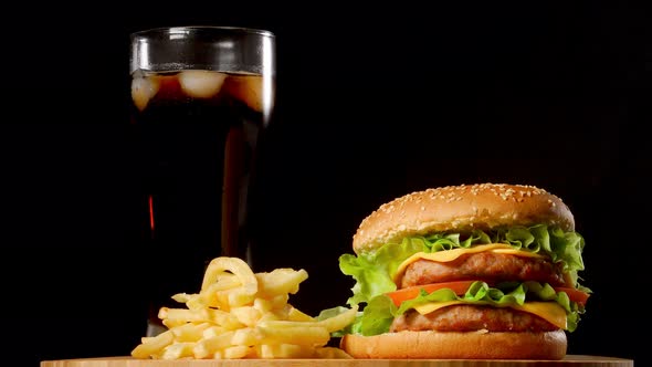 Burger with French Fries and a Glass with Ice Cola on a Black Rustic Background