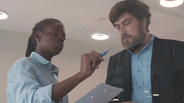 Two Business People Writing on Glass Wall