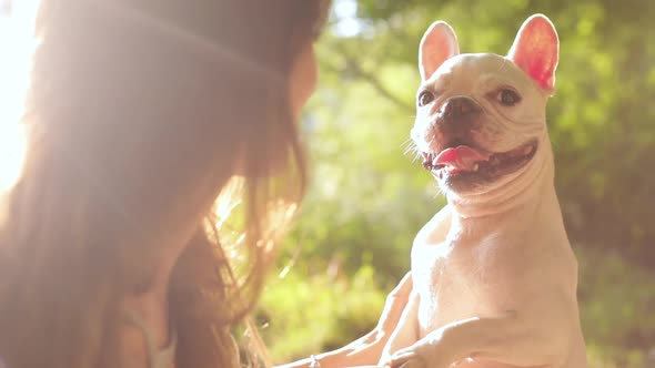 Brunette Girl Holding small Dog in her Arms.