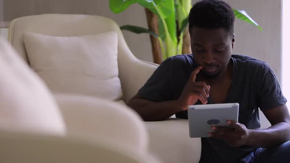 Afro Man Using Digital Tablet Sit By Couch at Home Spbi Young African Guy Holding Device Looking