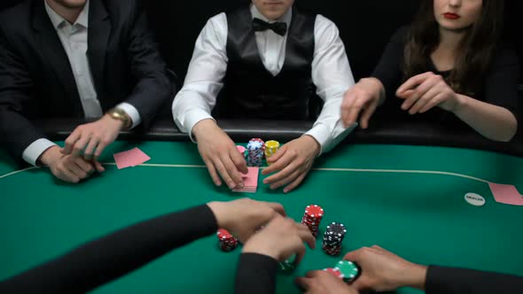 Players Betting and Poker Dealer Turning Up Community Cards on Casino Table