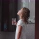 Little curly child girl rinses her mouth with water in bathroom, side view. - VideoHive Item for Sale