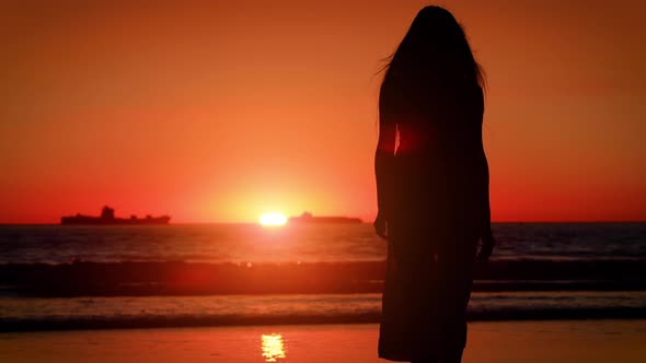 Asian woman enjoys a walk on the beach at sunset. Slow Motion.