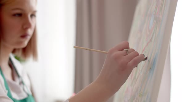 Female Artist Paints in Studio on Canvas with Brush Closeup of Hand Side View