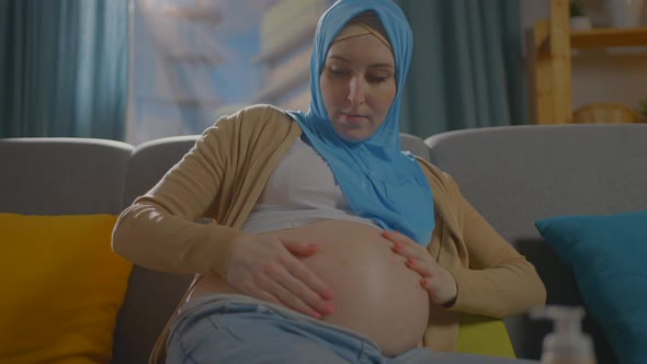 Pregnant Muslim Young Woman Uses Ointment or Body Lotion