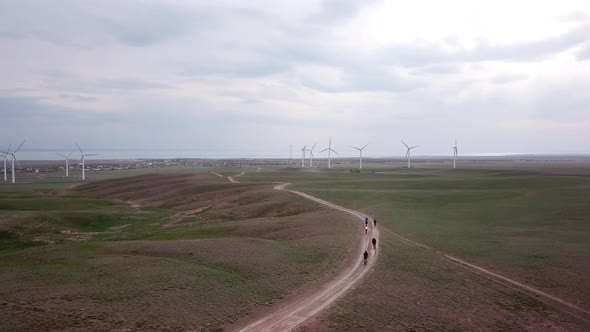 A Group of Cyclists Rides Along the Windmills