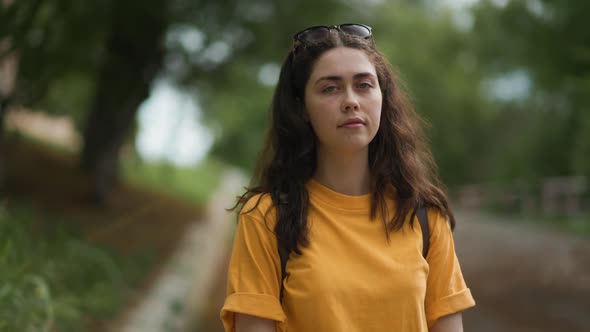 Summertime. Portrait of a young smiling Caucasian woman on the background of a park.