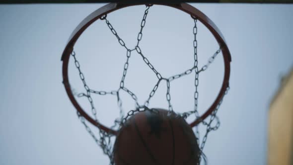 Extreme Closeup of Orange Ball Falling in Metal Basketball Net