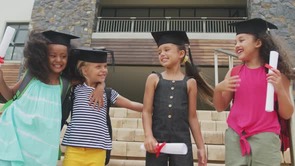 Video of happy diverse girls wearing graduation hats and holding diplomas