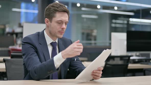 Businessman Reading Reports While Sitting in Office
