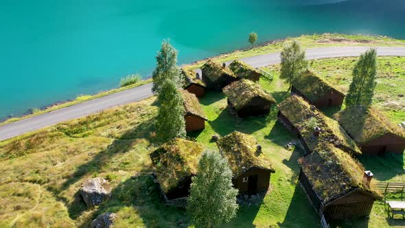 Grass roof house cluster on a meadow near a lake, Aerial view