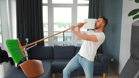 Man Cleaning the House and Having Fun Dancing and Singing with a Broom