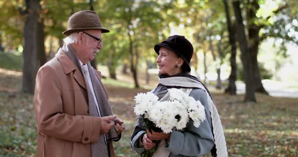 Happy Retired Couple in Love Having Joy During a Romantic Meet in Park