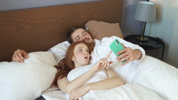 Young Happy Couple Makes Online Breakfast Caucasians Lying in Hotel Room Bed