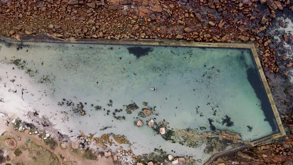 Aerial view of woman swimming in Glencairn pool, Cape Town, South Africa.