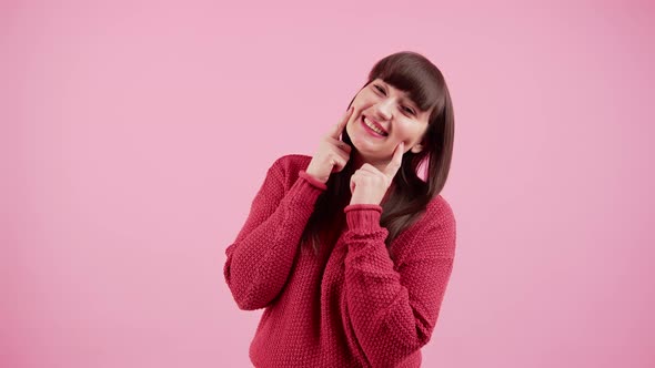 Cheerful Caucasian Millennial Girl Touching Her Cheeks in a Cute Kawaii Way While Standing in a