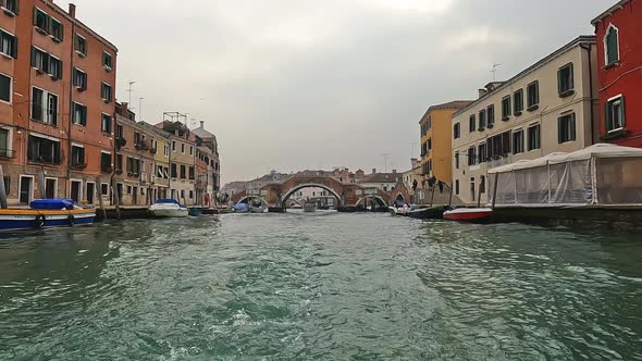 Water surface pov of Venice seen from sailing ferry boat with Ponte dei Tre Archi bridge in backgrou