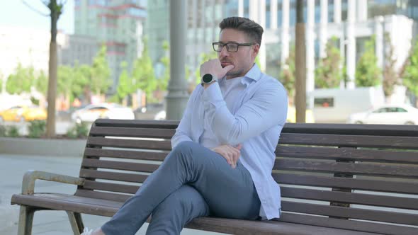 Pensive Man Thinking While Sitting Outdoor on Bench