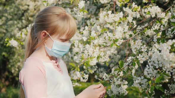 Sad Child in a Mask Near Flowering Trees