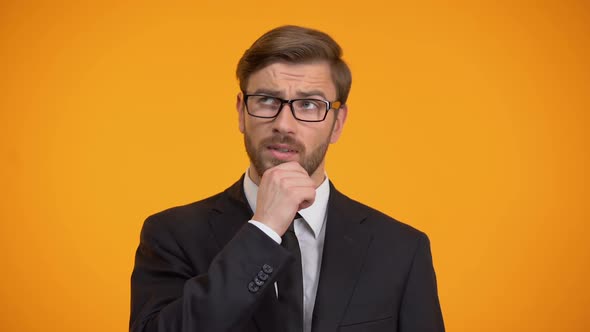 Pensive Male Thinking About Business Ideas for Start Up, Orange Background