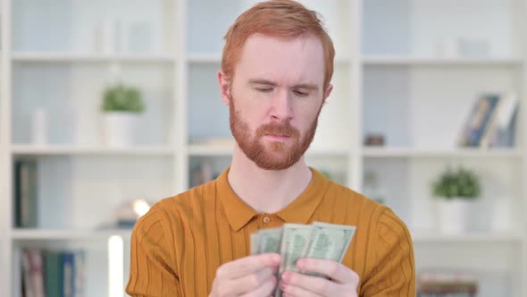 Portrait of Focused Redhead Man Counting Dollars 