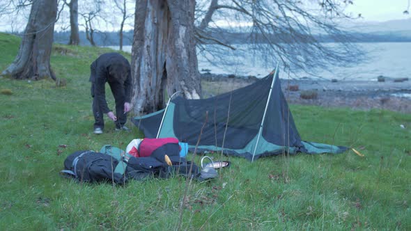 Young man pitching tent on island evening WIDE 4K