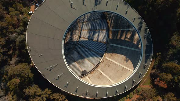 Aerial top down spinning over Quinta Vergara Amphitheater surrunded by tree forest in park, Viña del