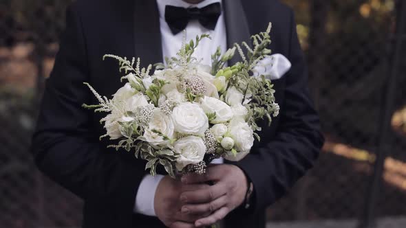 Groom with Wedding Bouquet in His Hands Outdoors Preparing to Go to Bride Closeup Slow Motion