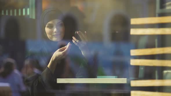 Beautiful Confident Muslim Female Applying Cosmetics, Sitting in Cafe, Coquette