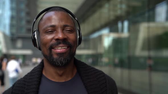 Portrait of Inspired Music Lover Man, Walking on City Street, Listening Song Through Wireless