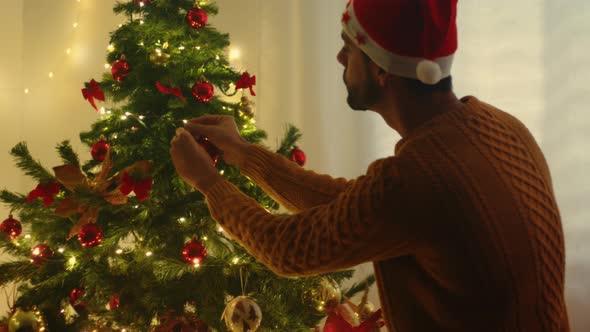 Guy Hangs Ball On Christmas Tree