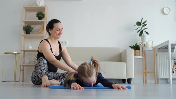 Woman Helping Daughter Stretching Legs Indoors