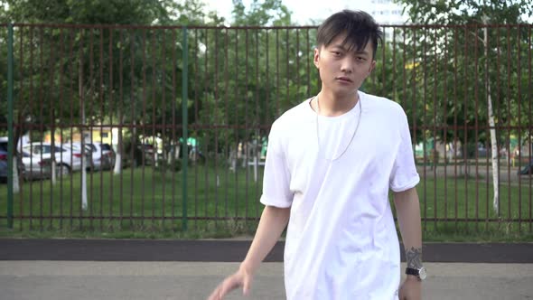 Young Asian Male Teenager with a Basketball Ball on a Street Playground