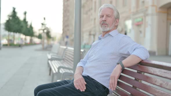 Old Man Looking at Camera While Sitting on Bench