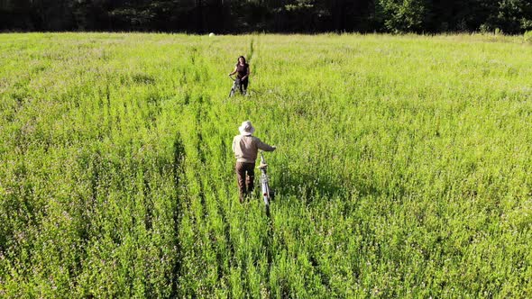 Couple of Friends on Bicycles Meeting in the Green Field and Shake Hands, Companion Friedship