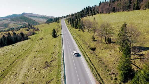 Aerial View White Car Travels in Beautiful Mountainous Terrain