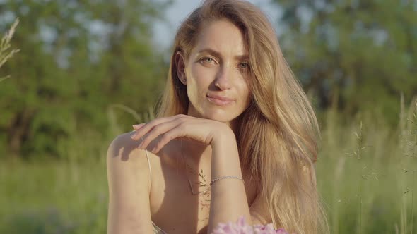 Portrait of Smiling Young Woman Posing at Sunset on Summer Meadow. Young Beautiful Brunette