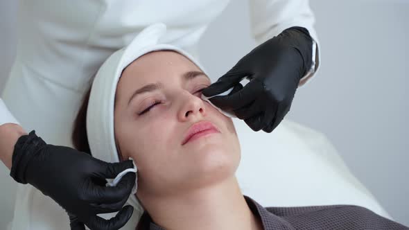 Beautician Cleaning Female Face with Cotton Pads After Procedure