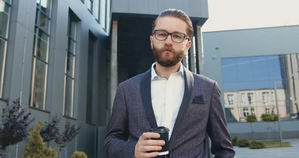 Businessman in Formal Clothes Walking Near Modern Office Building with Coffee