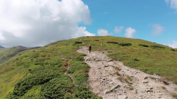 Aerial View of a Traveler with Backpack Climbing Along Mountain Slope, Epic Shot