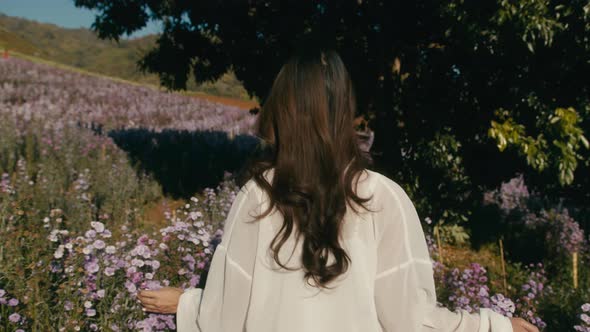 Young Asian Woman Walks in Flower Field on Sunset