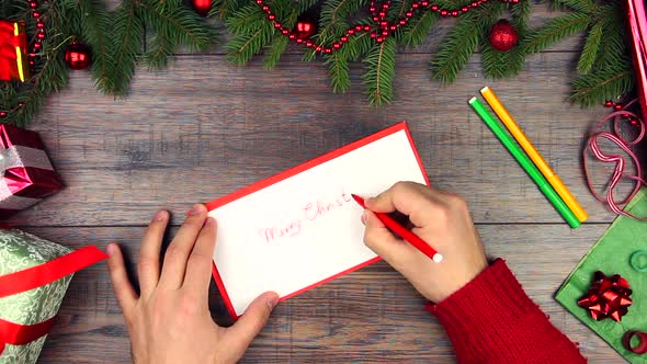 Hands writing Merry Christmas card