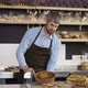 Young Handsome Man Salesman in the Apron Bringing Fresh Pies to the Counter in the Bakery Shop - VideoHive Item for Sale
