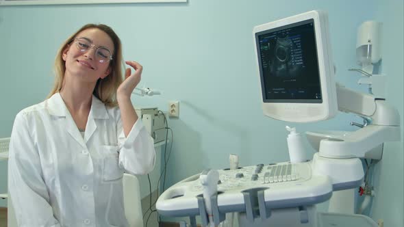 Smiling Female Doctor in Glasses Looking Into the Camera in Ultrasound Room