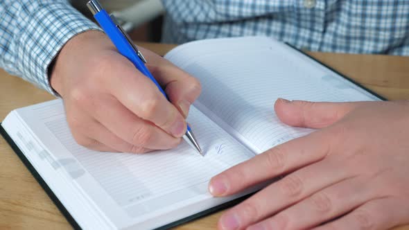 Close up businessman hands writes to-do list in notebook works at home office