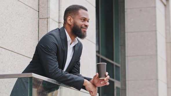 Smiling Young African American Corporation Employee Manager Businessman Drinking Coffee on Balcony