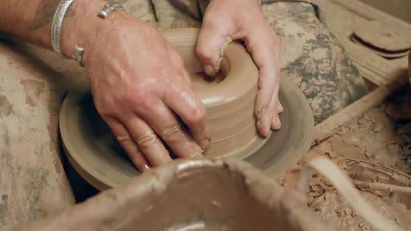 Skilled pottery master forming clay bowl on ancient kick operated revolving wheel