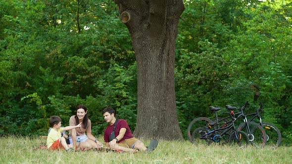 Sporty family relaxing and having picnic after biking