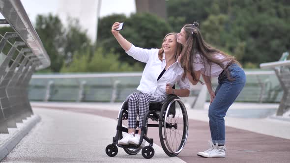 Joyful Girl with Mom on Wheelchair Taking Selfie