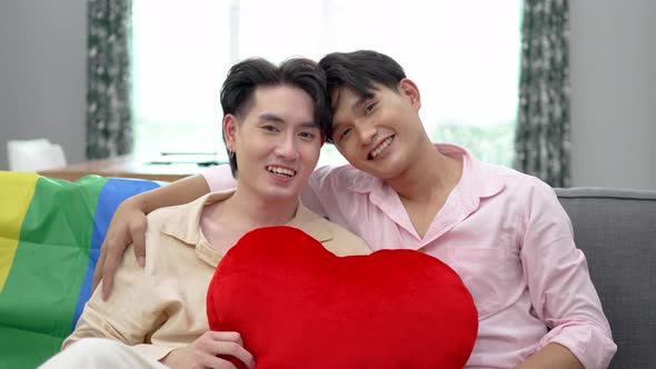 Portrait of Happy Asian gay couple embracing and showing their love with red heart pillows